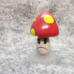 Fýlusveppur. Úr Cuphead tölvuleiknum. Hattur er með sterkum gormi og fjaðrar eins og bobblehead.